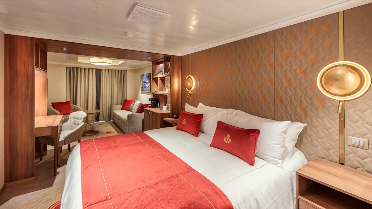 View of the bed, sofa and balcony of a Princess Grill Suite on a Cunard cruise ship